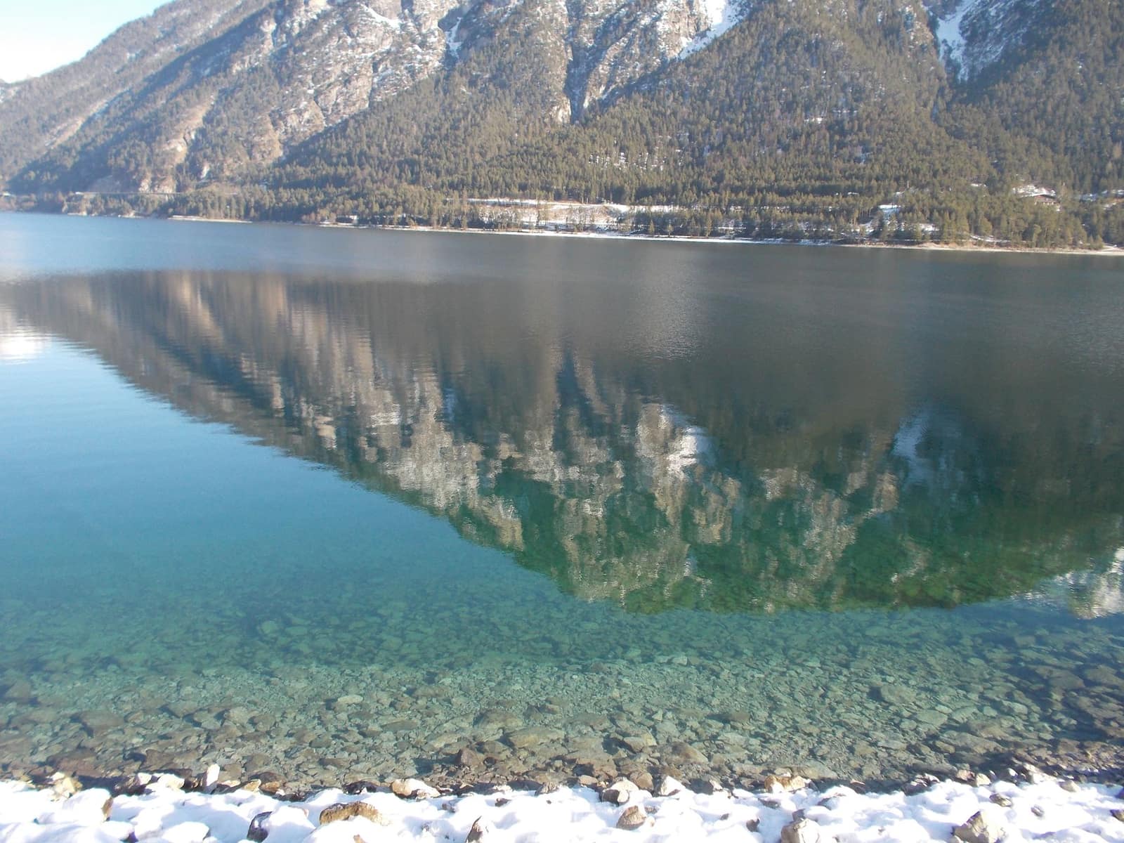 A clear mountain lake reflecting green hills